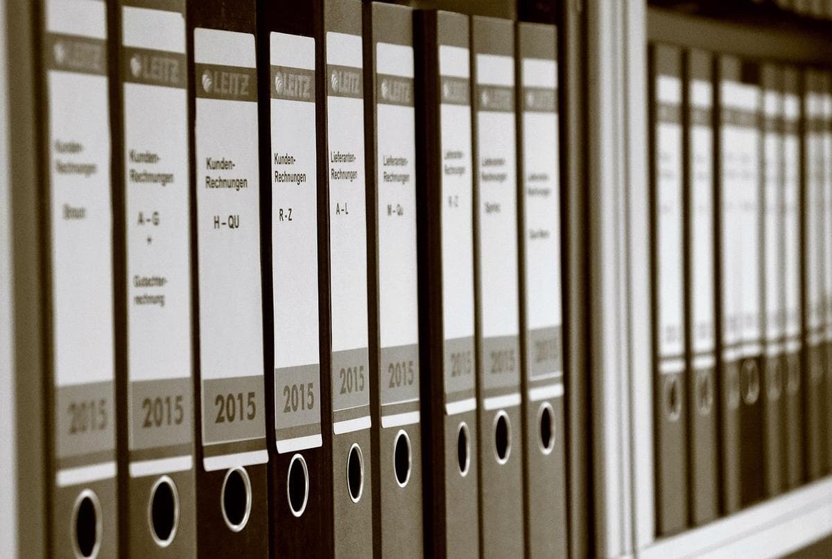 Une rangée de classeurs étiquetés archivant des dossiers sur une étagère — le stockage zero-knowledge garde vos dossiers scellés pour que vous seul puissiez les ouvrir.